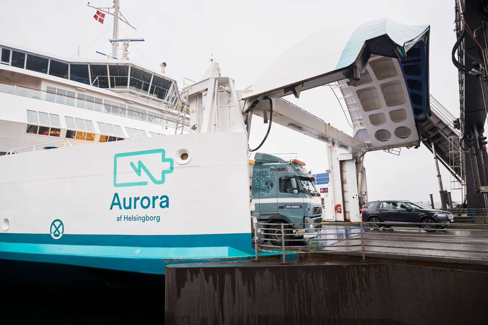 Færgen Aurora af Helsingborg lastes ved kajen med en lastbil og bil om bord under en grå himmel.