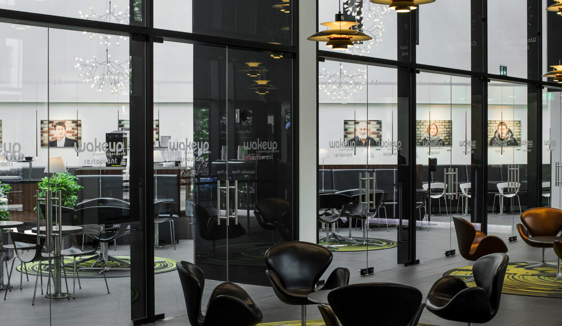 Moderne caféinteriør med sorte læderstole og glasvægge i mødelokale hos Wakeup Copenhagen.