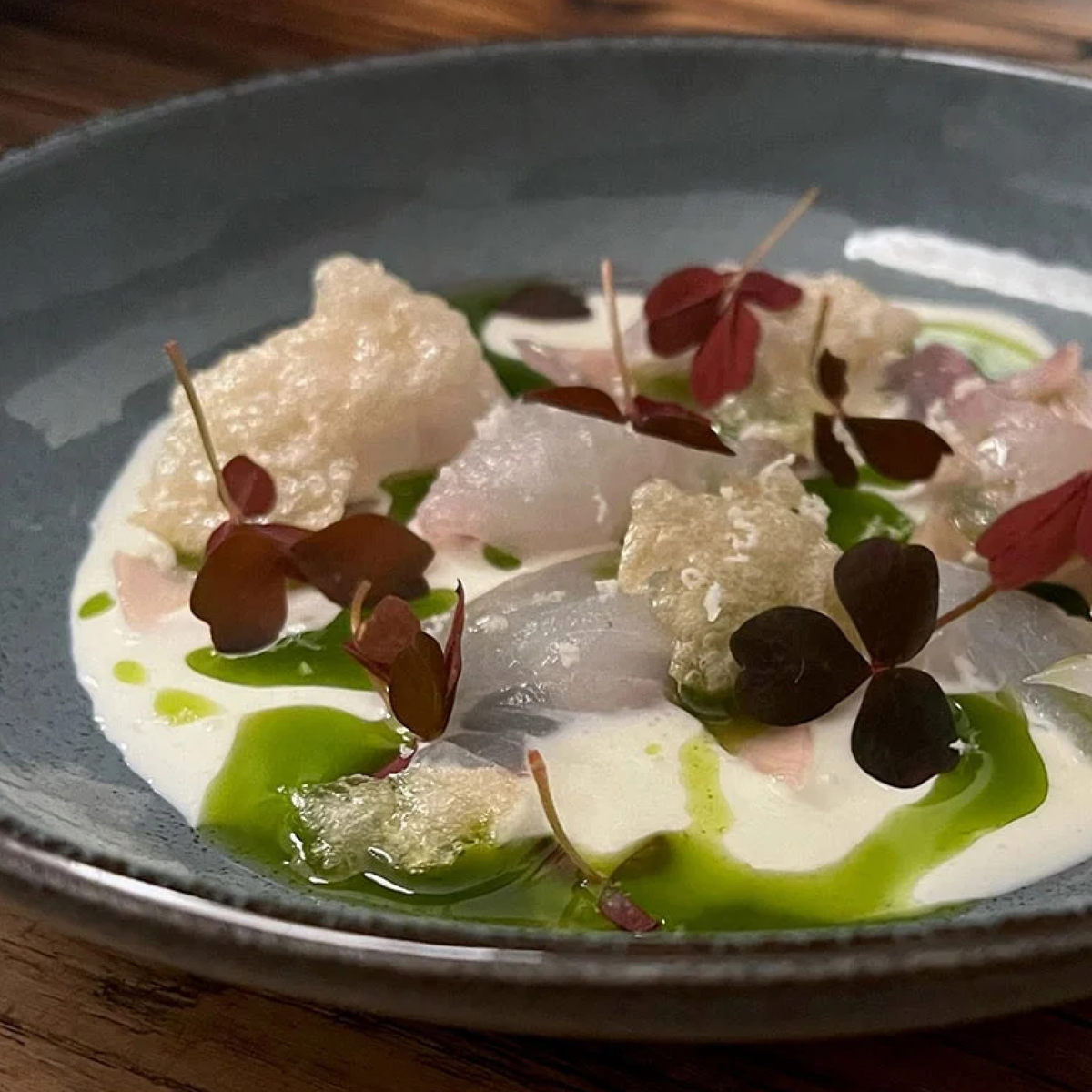 Råbiff på en elegant tallrik med krispiga brödsmulor, örtsås och röda örter, serverad på en elegant middag.