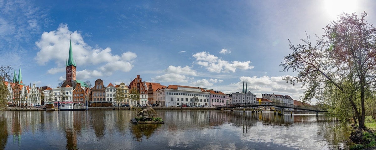Panoramautsikt över Lübeck med klart vatten i förgrunden.