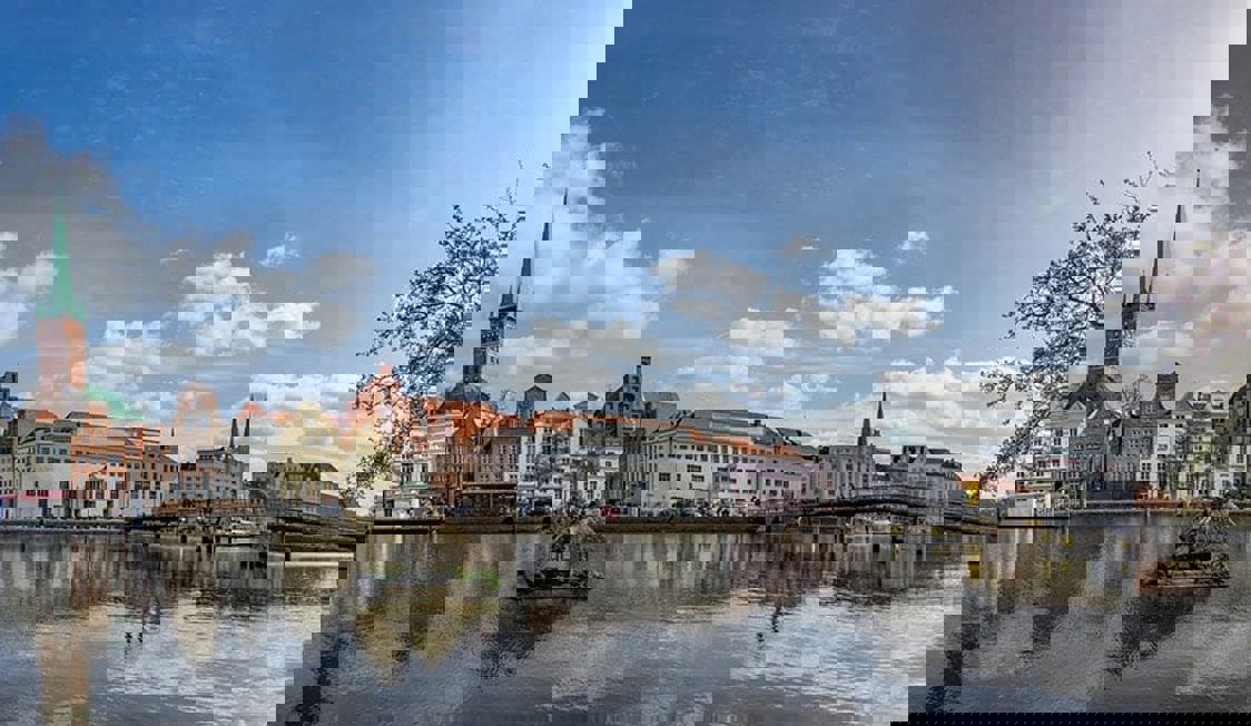 Panoramautsikt över Lübeck med klart vatten i förgrunden.