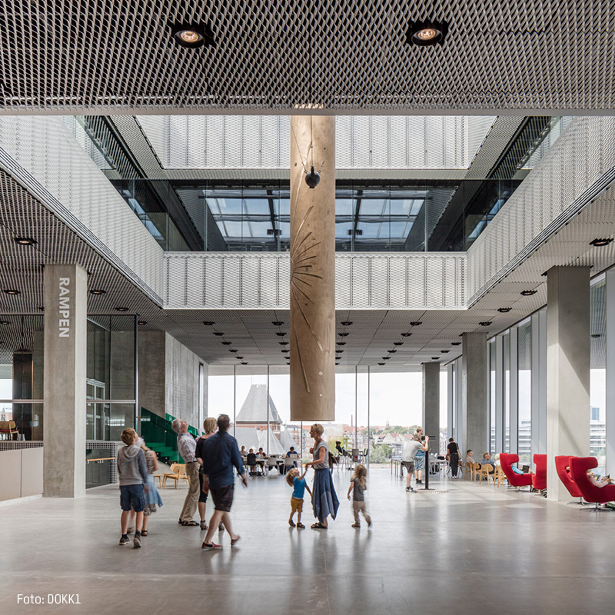 Indvendigt billede af Dokk1 med moderne design og besøgende, set i et lyst og rummeligt atrium med store vinduer.