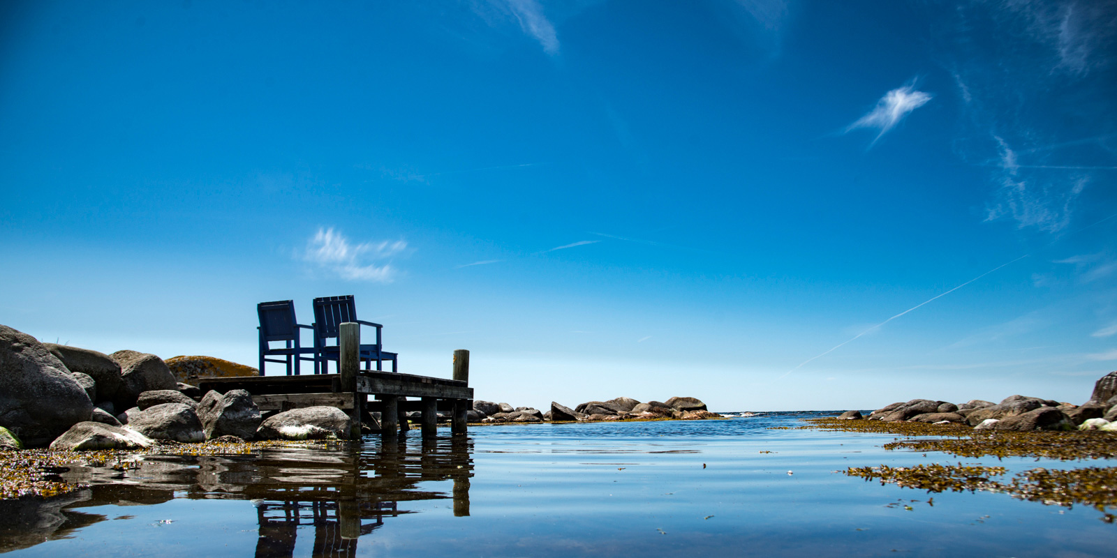 Et lille soldæk med to havestole står med retning mod udigten til havet.
