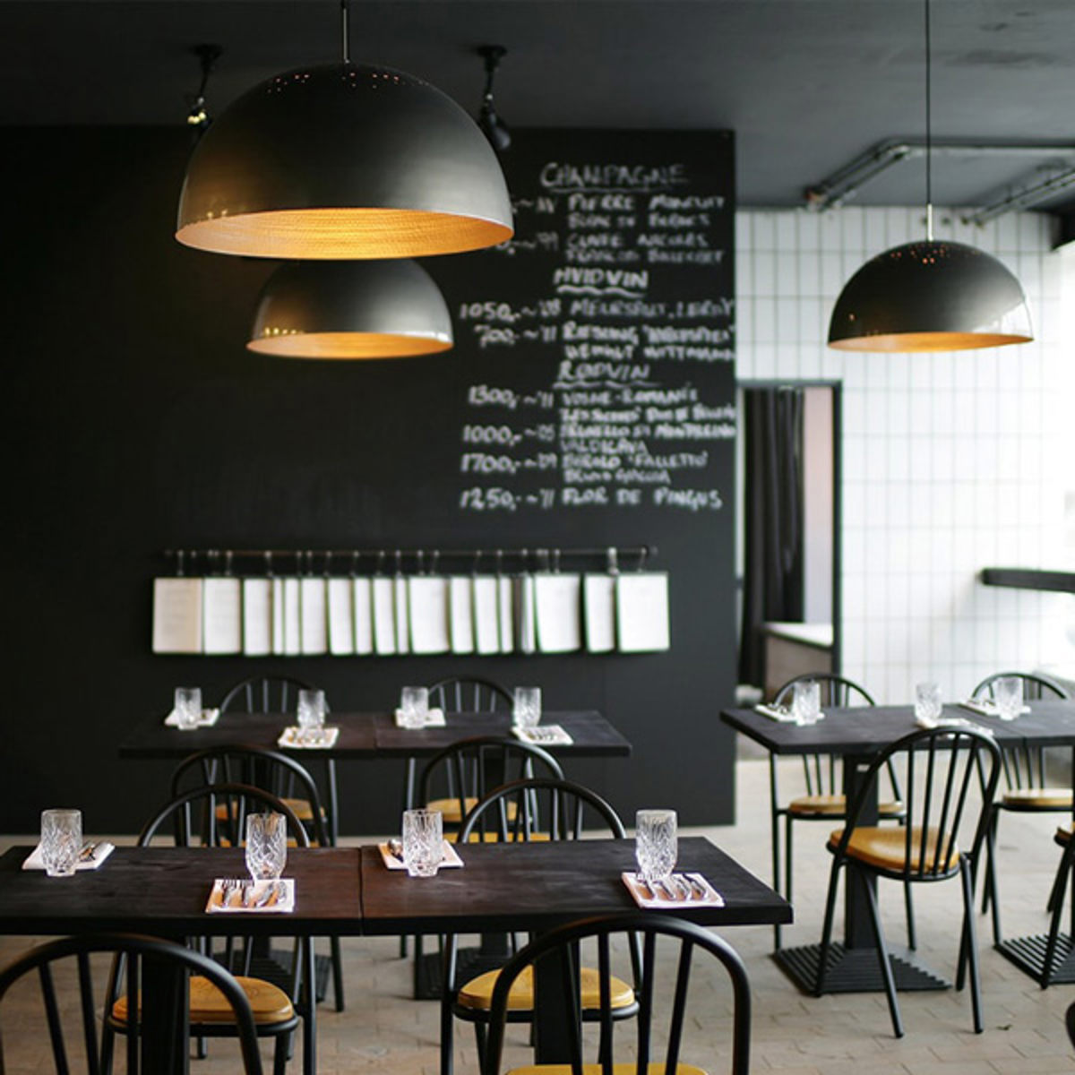 Inredningen av restaurangen Kodbyen med svarta stolar och bord i en modern och stilren miljö.