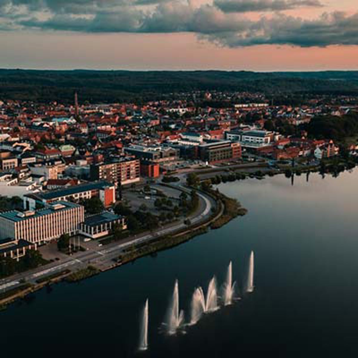 Luftfoto af Aarhus ses i aftentimerne med spejlblankt hav.