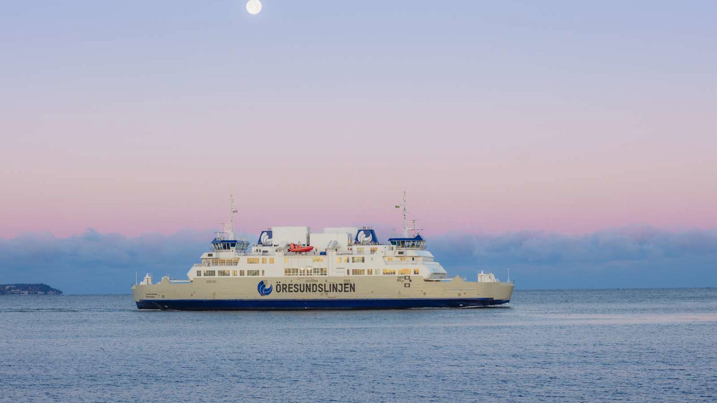Öresundslinjen færge sejler på åbent hav under solnedgang med månen synlig på himlen.