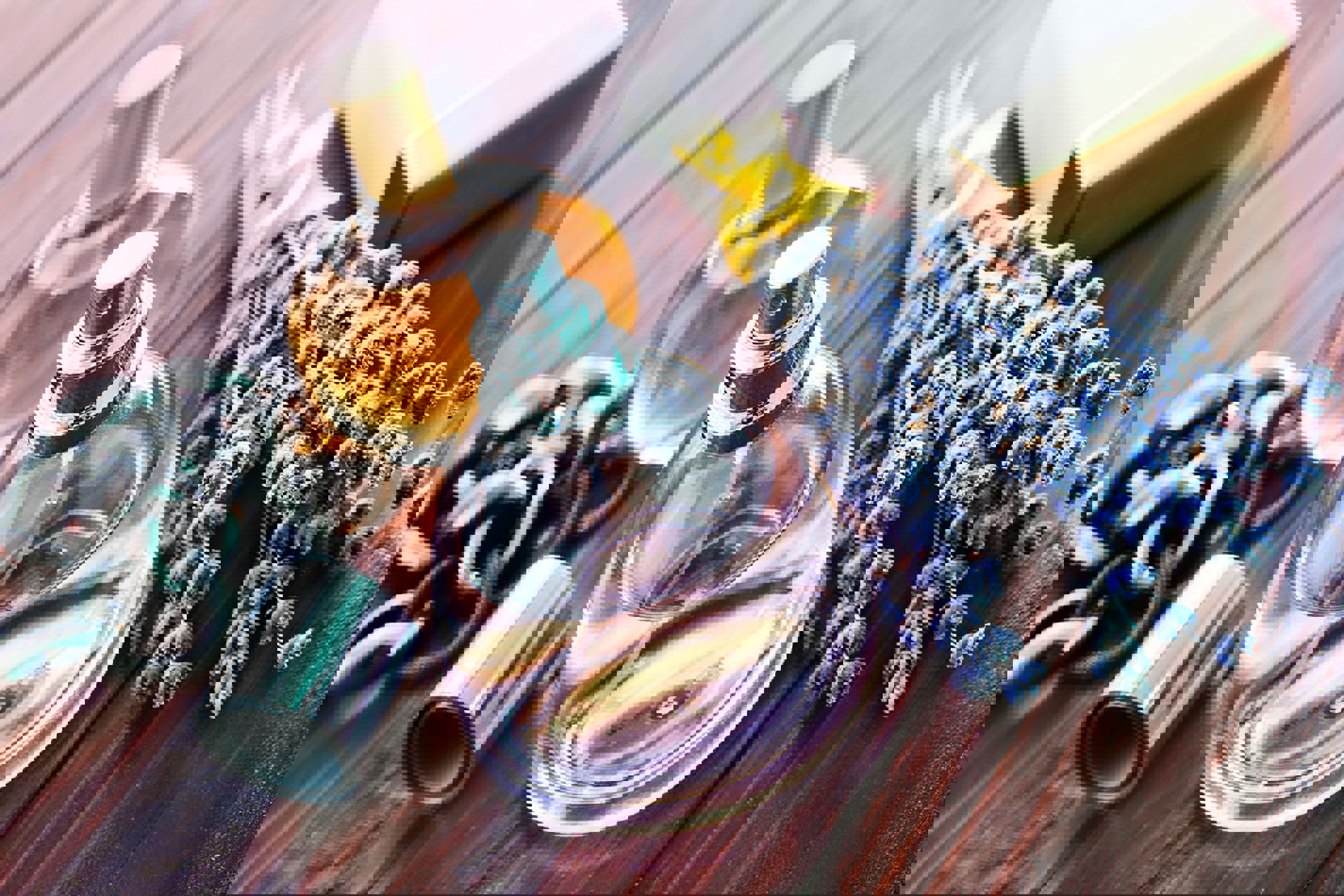 En person klipper en frisk grøn buksbom til dekorative kranse ved et bord fyldt med blomsterdekorationer.