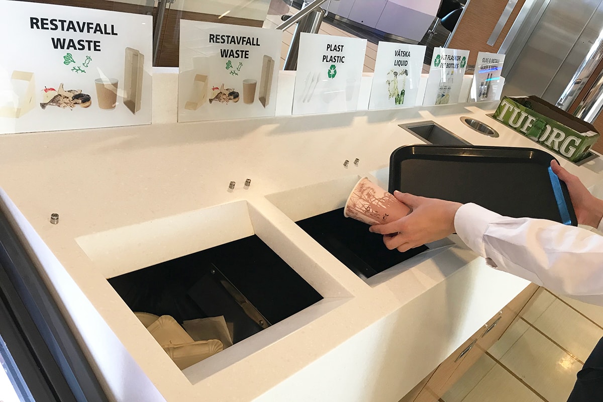 En person slänger skräp vid sopsortering.