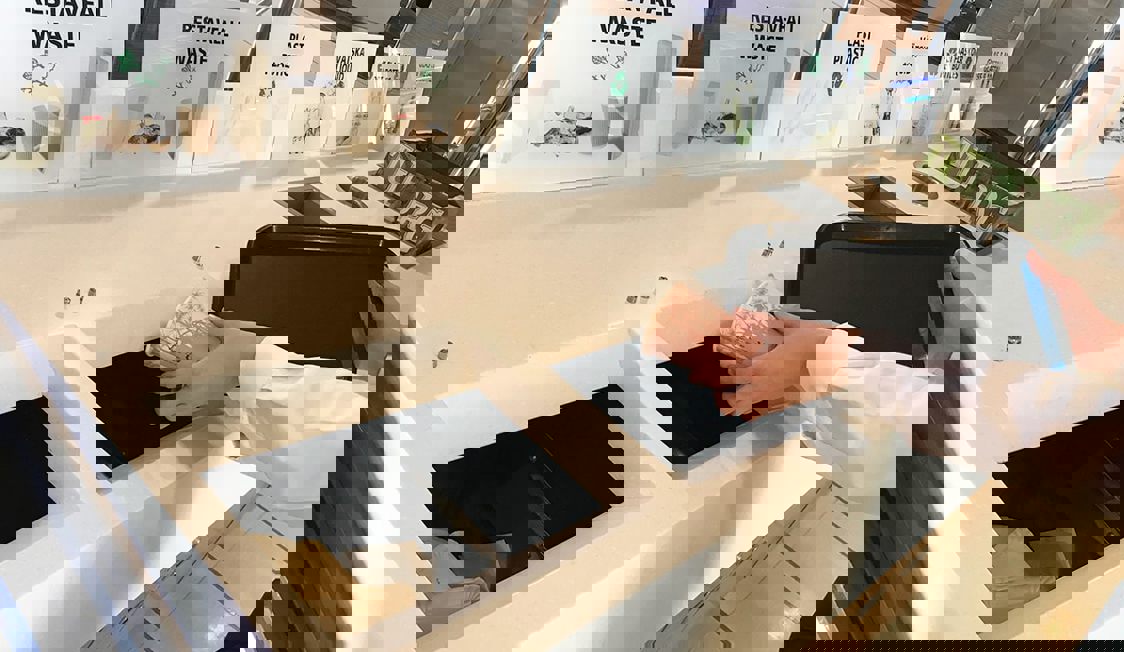 En person slänger skräp vid sopsortering.