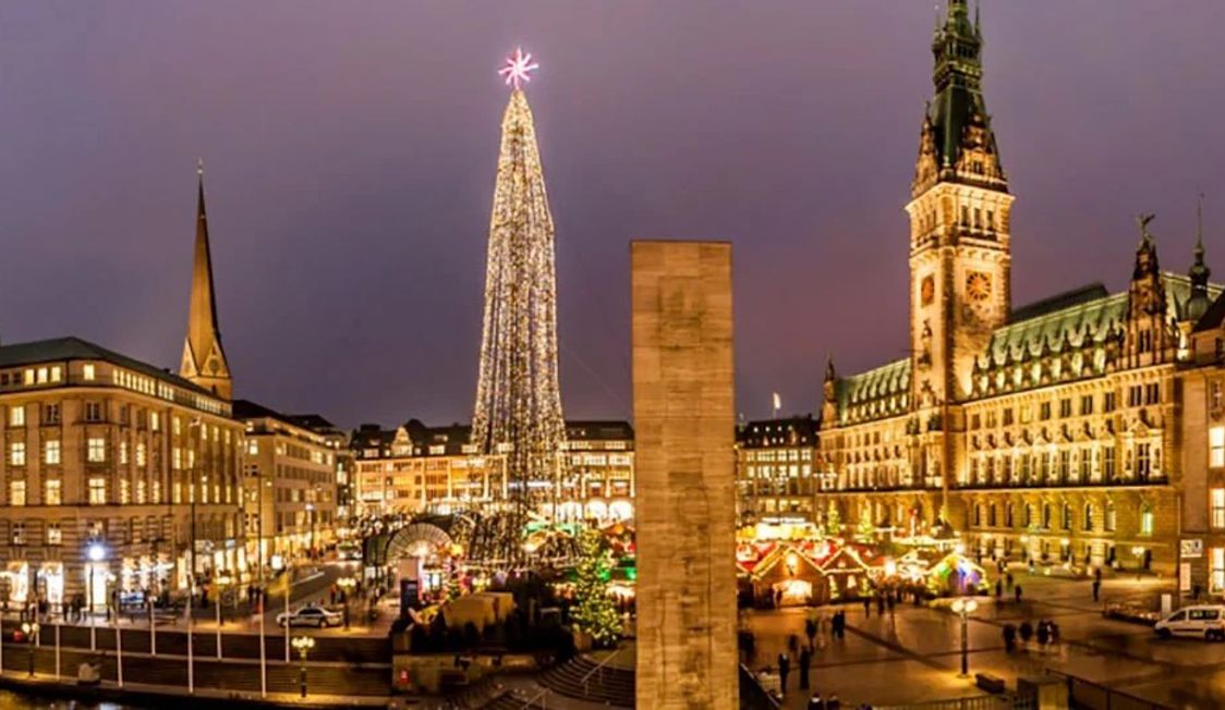 Julgran tänd vid skymningen i centrala Hamburg, omgiven av traditionell stadsarkitektur.