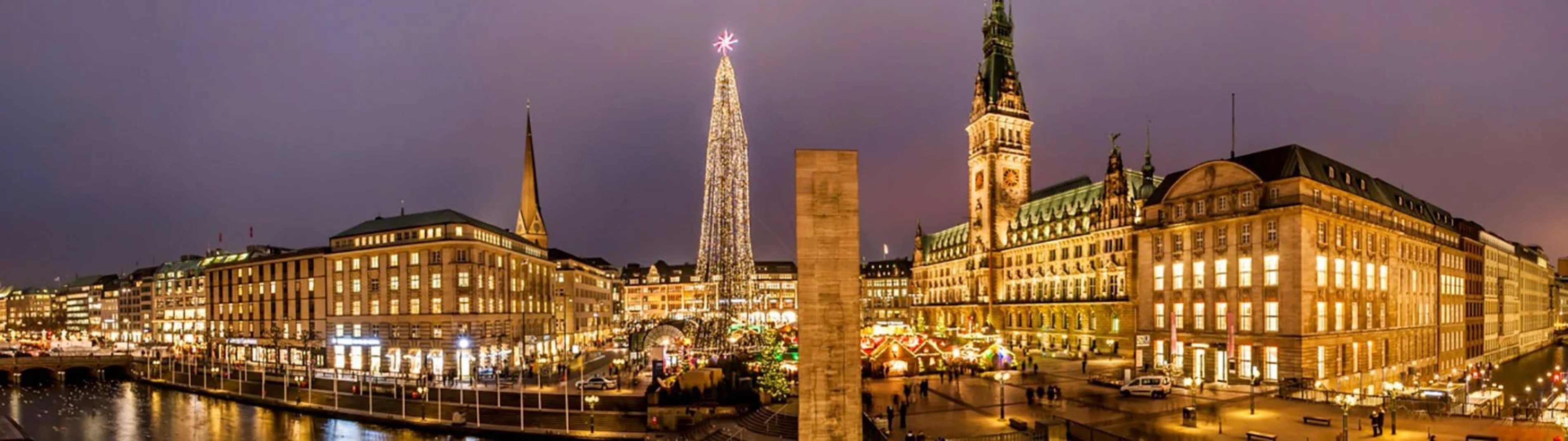 Julgran tänd vid skymningen i centrala Hamburg, omgiven av traditionell stadsarkitektur.